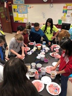 Students working on crafts with paper plates in classroom