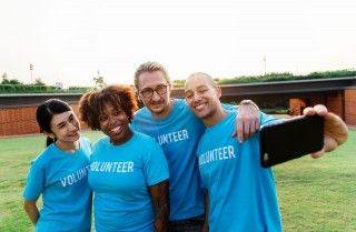 Two women and two men in volunteer shirts posing for a picture