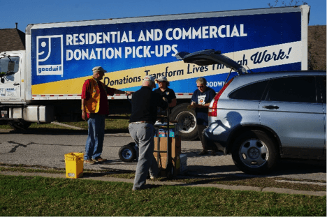 Large goodwill truck and group of people loading up a car with donations