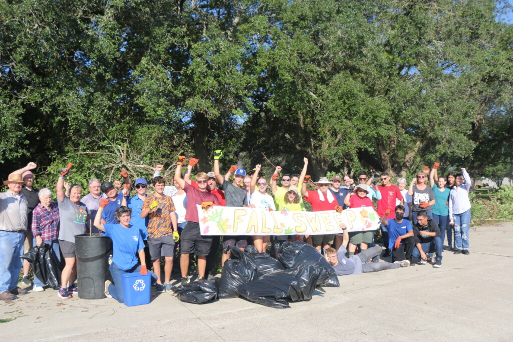 a cleanup crew in Dickinson, TX celebrates with a banner and bags of collected litter