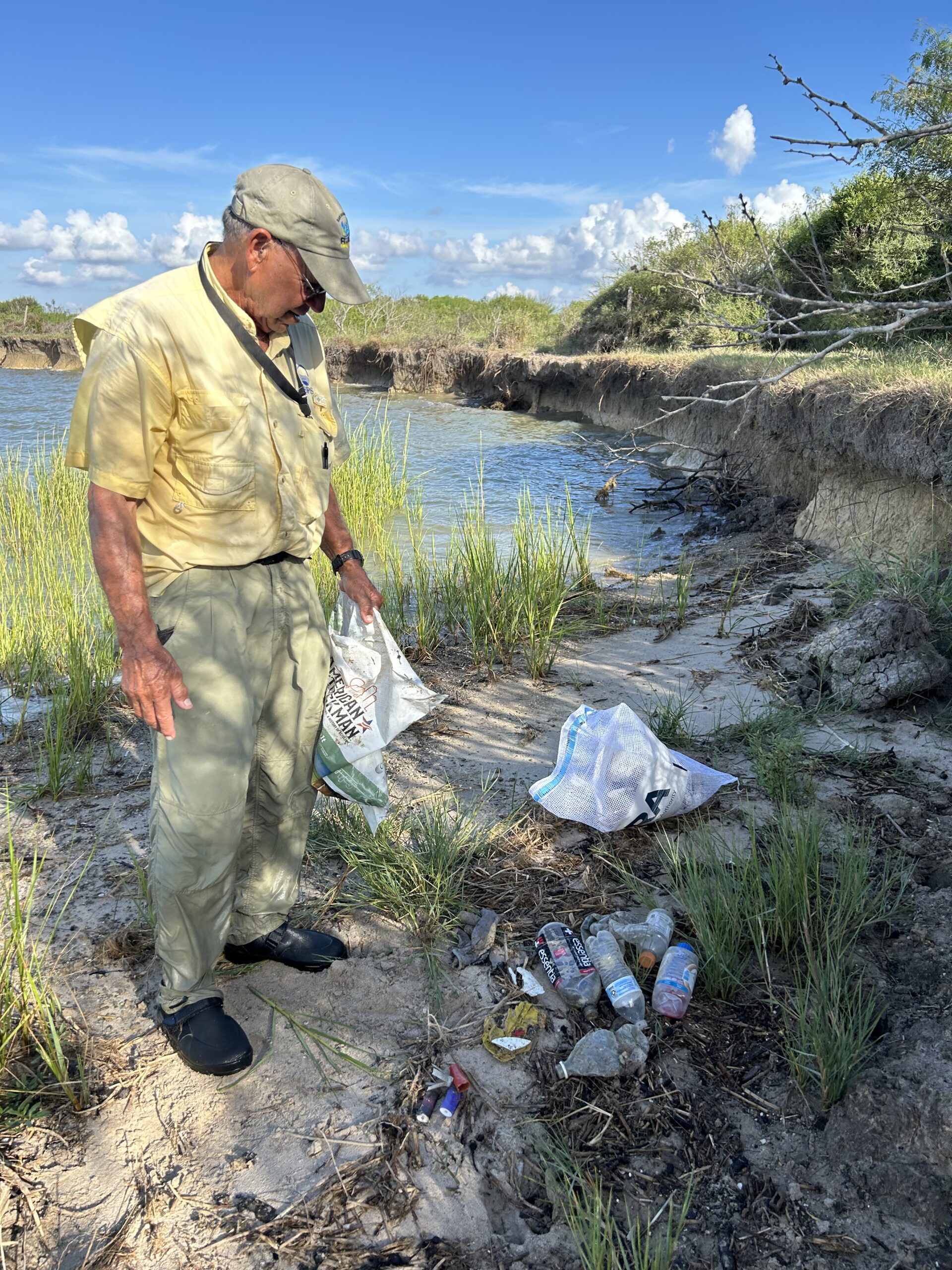 Attendee collecting plastic bottle trash from the sandy shore.