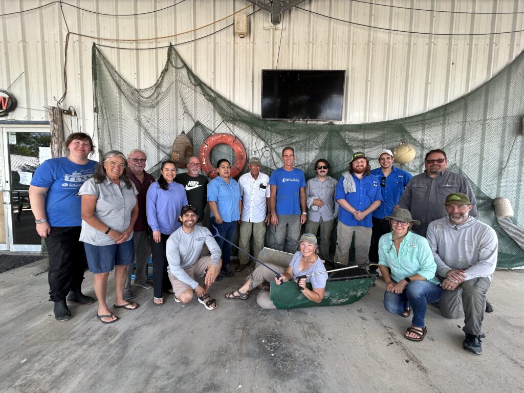 Participants from the cleanup pose in front of building wall strewn with fishing nets.